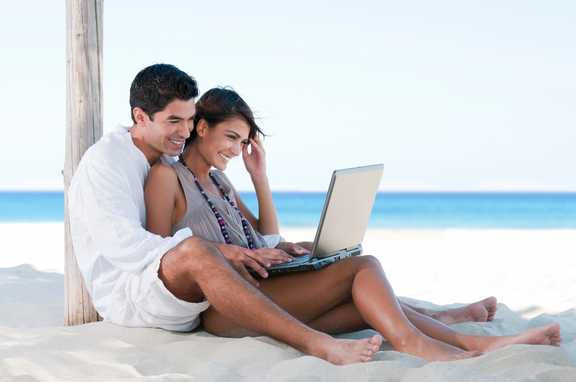 couple with computer on beach
